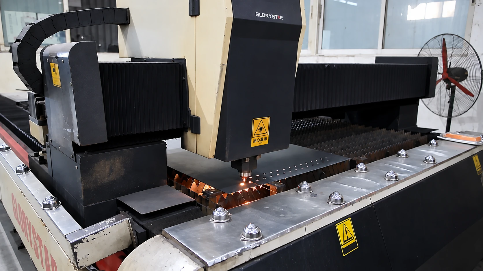 Laser cutting head working on sheet metal on a flat cutting bed