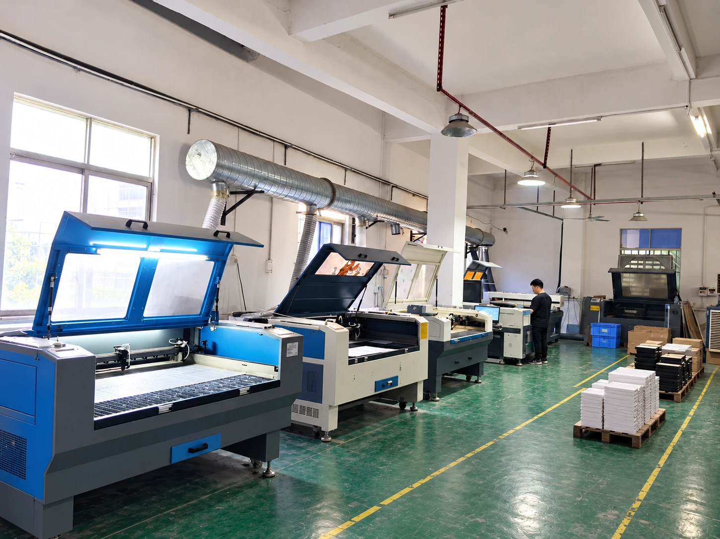 Laser cutting and engraving machines with raised lids and extraction ducts in an acrylic workshop